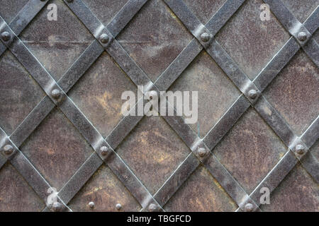 Fragment of a metal door with iron stripes on rivets in the old city Stock Photo