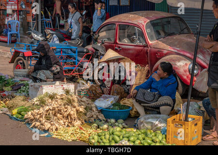 Old women selling fruits and vegetables near Daoheuang Market in Pakse, Laos backgroung VW Beetle, Oldtimer Stock Photo
