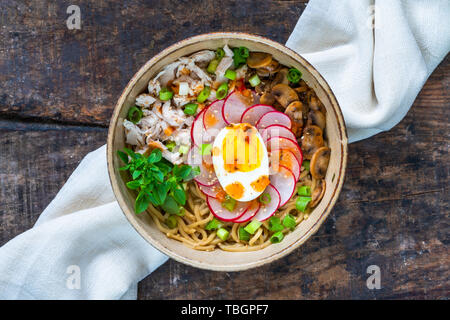 Ramen noodles with chicken, egg, mushrooms and radish sprinkeld with chili sauce and sesame seeds - top view Stock Photo