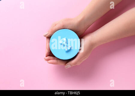 Female hands with gift box on color background Stock Photo