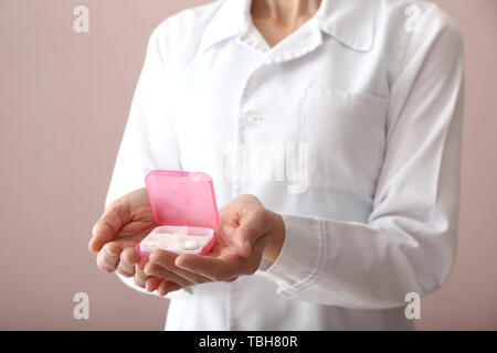 Doctor holding container with pills on color background Stock Photo
