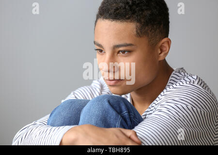 Sad African-American teenage boy on grey background Stock Photo