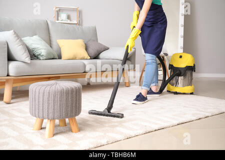 Female janitor with vacuum cleaner in room Stock Photo