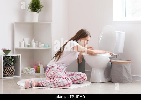 Pregnant woman suffering from toxicosis near toilet bowl in bathroom Stock Photo