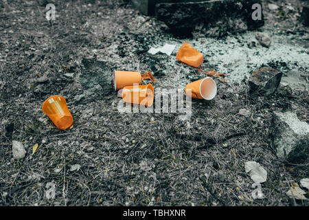 Orange disposable Plastic glass or cups used for drinking water in a bin - Environmental problem concept. Non-compostable waste. after a picnic. natur Stock Photo