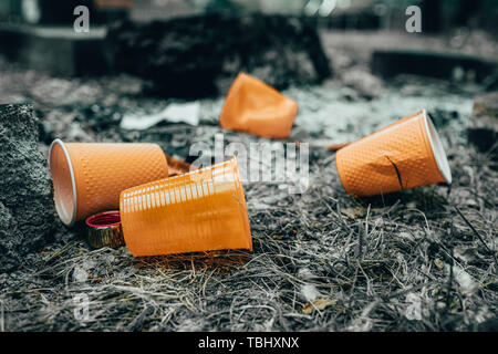 Orange disposable Plastic glass or cups used for drinking water in a bin - Environmental problem concept. Non-compostable waste. after a picnic. natur Stock Photo