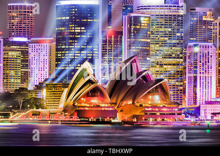 Wall of high-rise office building towers of Sydney city CBD on waterfront of Sydney harbour during Vivid Sydney light show with blue laser beam lights Stock Photo