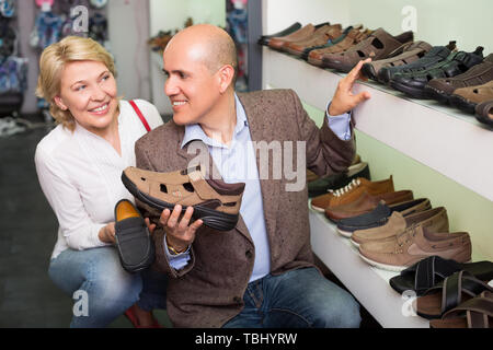 Happy woman selecting shoes for man in shoes departament Stock Photo