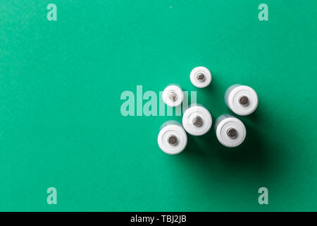 white batteries on a green background, top view. space for text Stock Photo