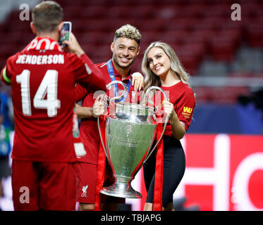 Liverpool's Alex Oxlade-Chamberlain (centre) celebrates with the trophy and Perrie Edwards (right) as team-mate Jordan Henderson (left) takes a picture during the UEFA Champions League Final at the Wanda Metropolitano, Madrid. Stock Photo