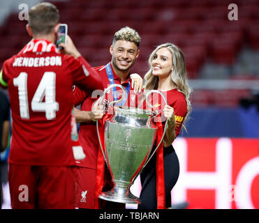 Liverpool's Alex Oxlade-Chamberlain (centre) celebrates with the trophy and Perrie Edwards (right) as team-mate Jordan Henderson (left) takes a picture during the UEFA Champions League Final at the Wanda Metropolitano, Madrid. Stock Photo