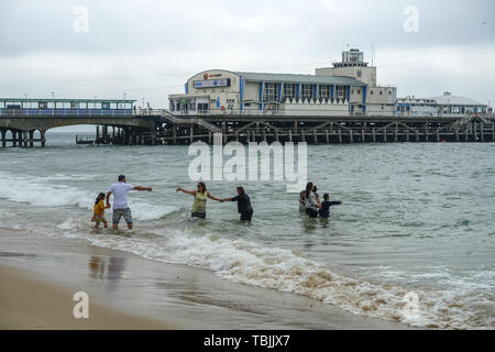 Bournemouth, Dorset, UK, 2nd June 2019. A cool start in the south of England meant that some visitors to the beach were well wrapped up in coats and hoodies. This family took to the sea fully clothed. The forecast was for 29 degrees Celsius but has only reached 20 degrees mid morning with a cool wind. Credit: Mick Flynn/Alamy Live News Stock Photo