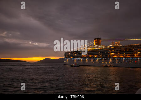 SANTORINI GREECE - OCTOBER 24 2018: Illuminated cruise ship moored in the bay at sunset Stock Photo