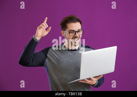 Thoughtful male programmer with laptop on color background Stock Photo