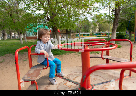 boy on the playground rides on a swing Stock Photo