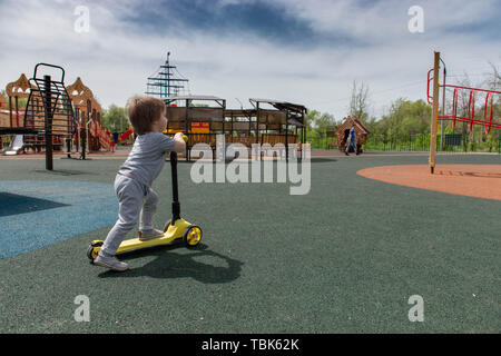 boy on the playground riding a scooter Stock Photo