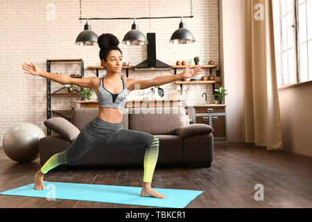 Sporty African-American woman practicing yoga at home Stock Photo