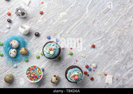 Tasty Easter cupcakes with candies on white table Stock Photo