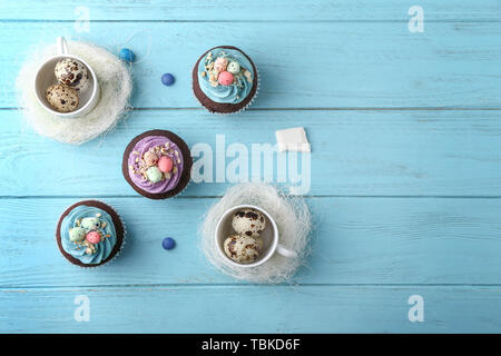Tasty Easter cupcakes with eggs on color table Stock Photo