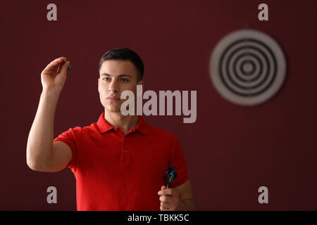 Young man playing darts indoors Stock Photo