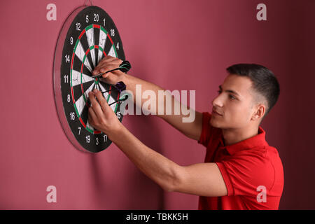 Young man playing darts indoors Stock Photo