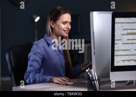 Female programmer working in office at night Stock Photo