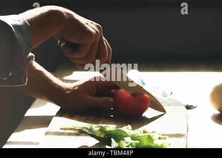 Handsome mature man preparing salad in kitchen Stock Photo