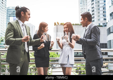 Portrait of successful group of business people at outdoor urban. Happy businessmen and businesswomen raising hand as team in satisfaction gesture. Su Stock Photo