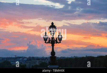 Paris skyline at sunset, with lamp post of Alexandre III bridge, Paris, France