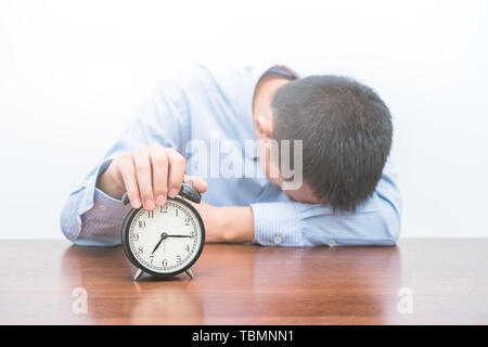 A tired young man holds the alarm clock Stock Photo