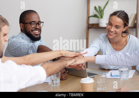 Happy smiling corporate diverse team joining hands together showing unity Stock Photo