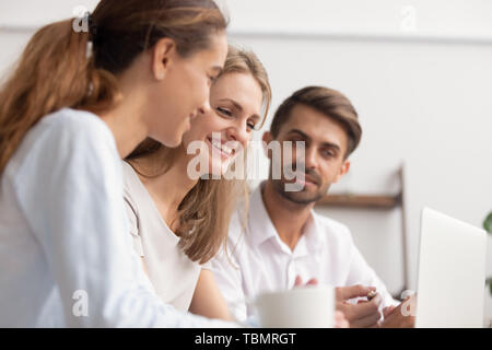 Joyful office employees having fun looking at laptop screen Stock Photo