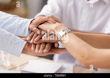 Close up view diverse business people putting stacked hands together Stock Photo