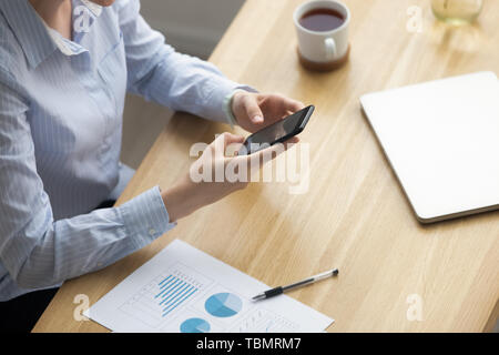 Businesswoman sitting at desk chatting using mobile phone Stock Photo