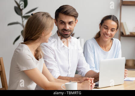 Businesswomen and businessman having informal talk sitting at office desk Stock Photo