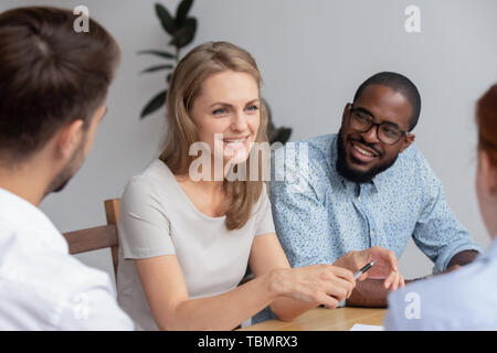 Happy smiling young woman talking with coworkers at work Stock Photo