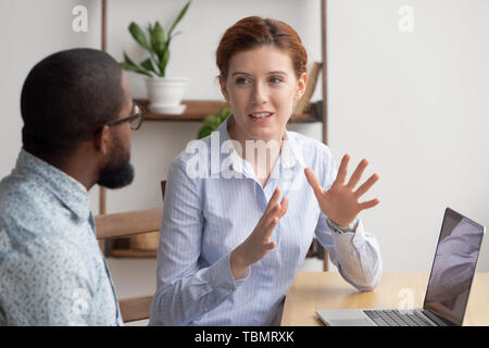 Two diverse businesspeople chatting sitting behind laptop in office Stock Photo
