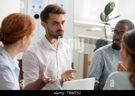 Serious businessman talking with group of business partners at meeting Stock Photo