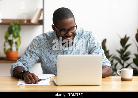 Head shot smiling african-american manager using laptop looking at screen Stock Photo