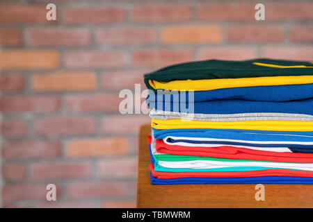 Stack of folded clothes on table indoor.Fresh folded cotton clothing Stock Photo