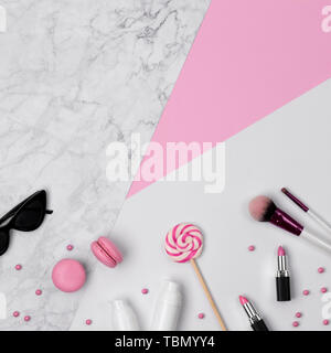 Top view of woman's beauty desk with accessories, decorative cosmetic  and sweets on pink, marble and white pastel table. Flat lay background. Stock Photo