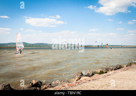 Windsurfer surfing the wind on waves on a lake on a summer day. Recreational water sport. Stock Photo