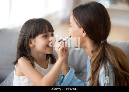 Funny young mom and preschooler daughter do makeup together Stock Photo