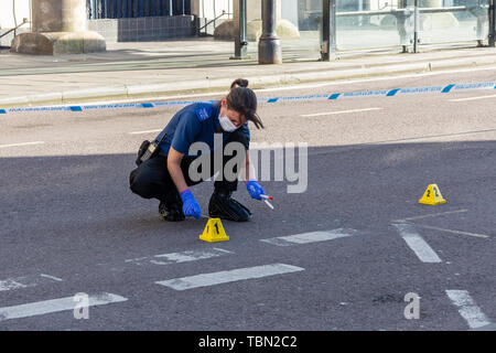 A CSI for the Wiltshire police with footcovers gloves and facemask is using swabs to collect blood evidence after an incident involving a knife Stock Photo