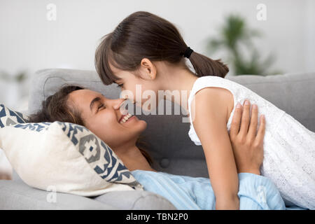 Loving young mom and little daughter relax on couch cuddling Stock Photo