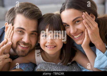 Cute preschooler girl hug parents posing for picture together Stock Photo