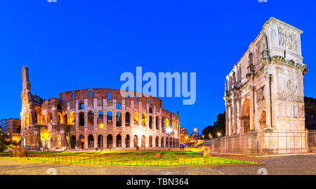 Rome, Italy: Night view of  The Arch of Constantine next to the Colosseum after sunset over a blue sky. Colosseum is an elliptical amphitheatre or the Stock Photo