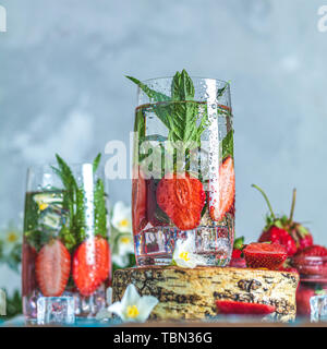 Detox infused water with strawberry and mint in highball glasses on blue concrete table background, copy space. Cold summer drink. Mineral water. Stock Photo