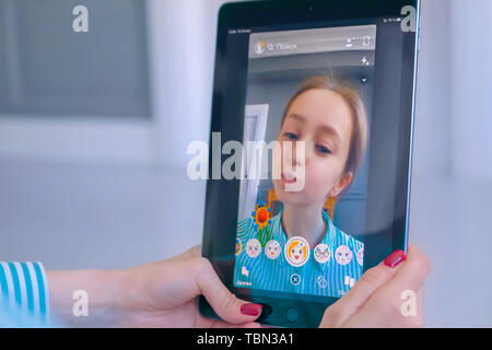 Woman using Snapchat multimedia messaging app with face mask on tablet Stock Photo