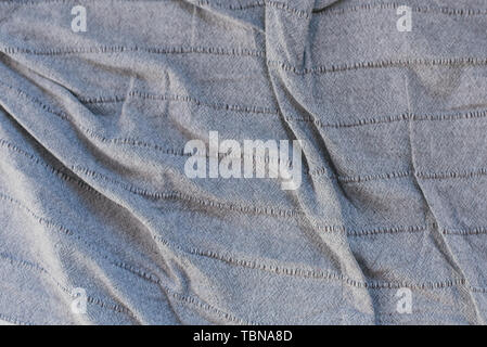 crumpled gray fabric. folds on a gray bedspread. texture of crumpled fabric. blue shadow from the folds. Stock Photo
